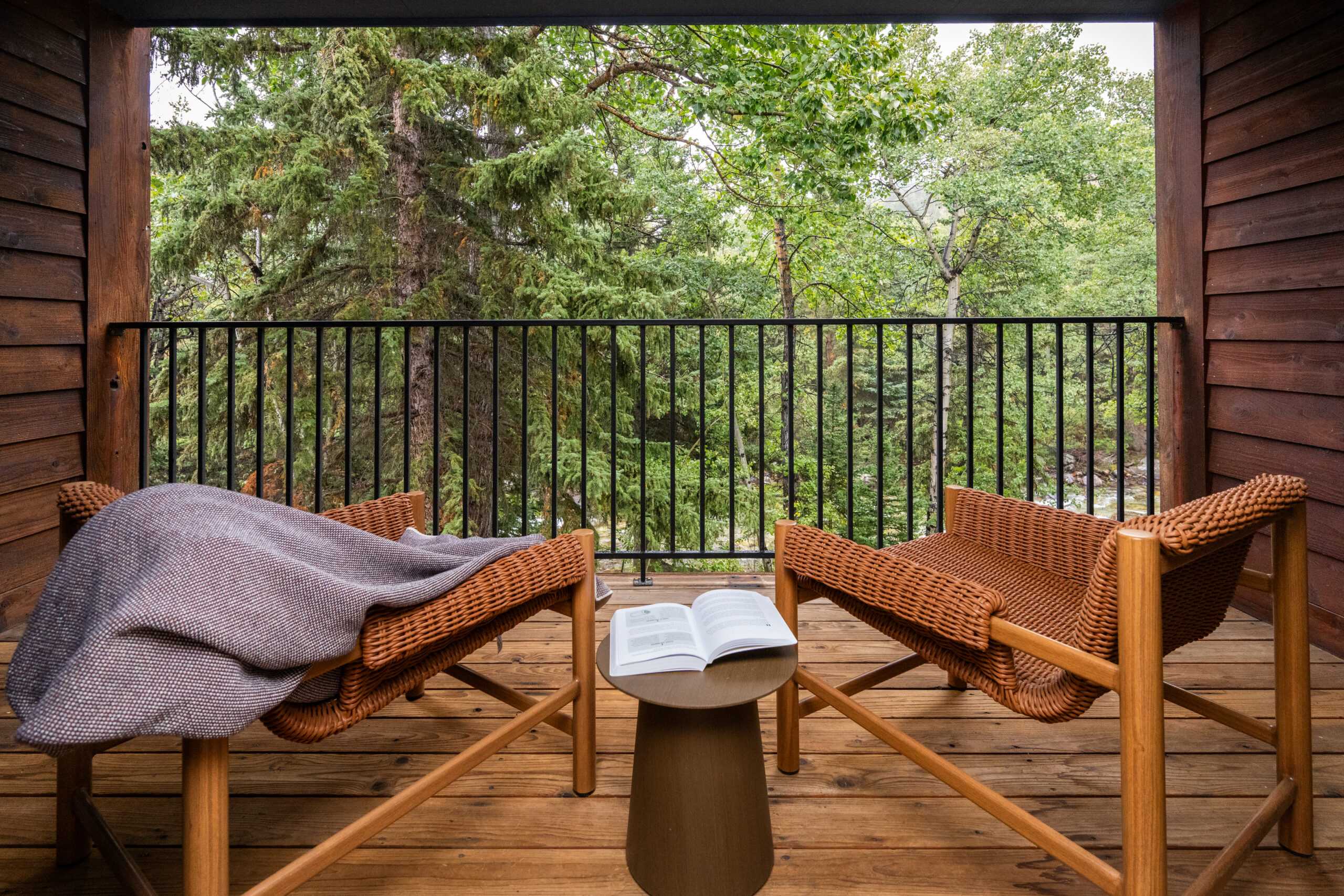 Two chairs on a balcony with a book open and blanket